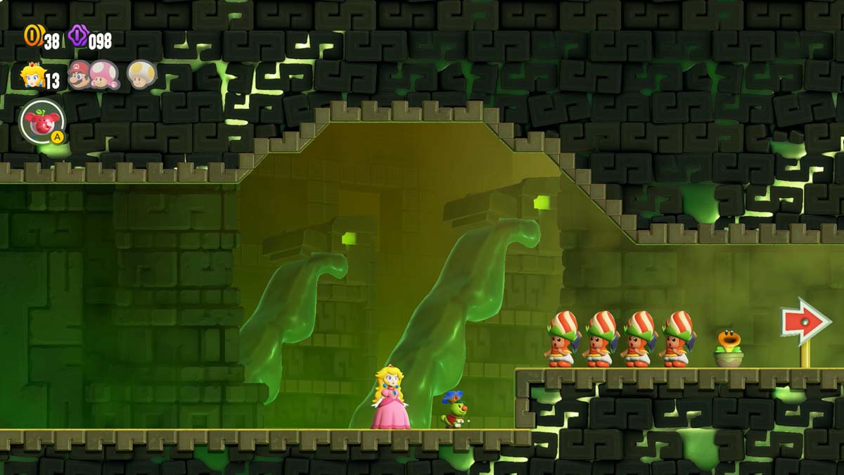 スーパー マロ ブラザーズのワンダー ピーチ姫と保護ヘルメットをかぶったキャラクターのグループが、幽霊のような緑がかった城の廊下で矢印が示す方向を見つめています。