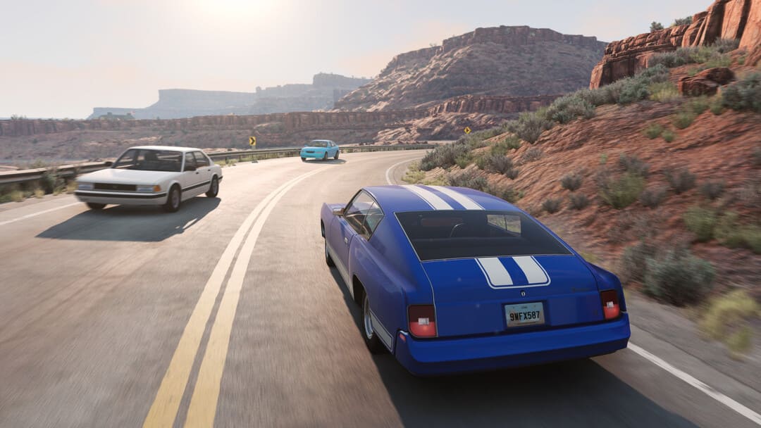 ゲームBeamng.Driveのスクリーンショット。砂漠のクリフサイドカントリーハイウェイを運転する白い垂直ストライプを備えた青い車を示すドライブ